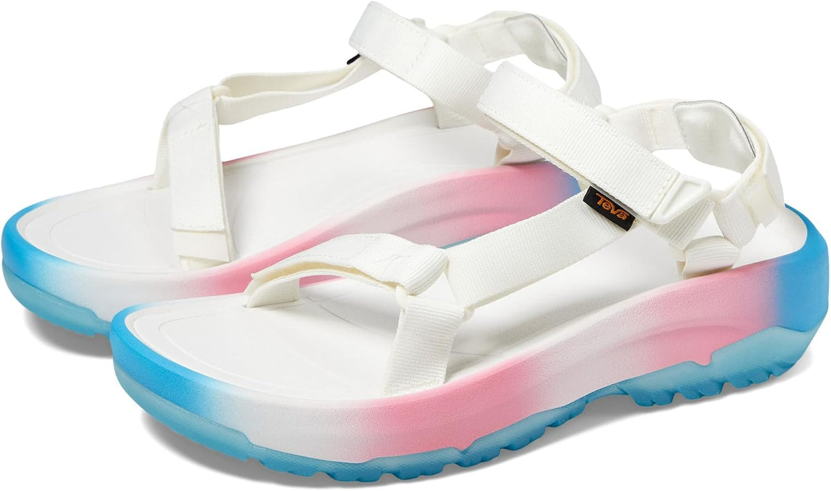 A pair of Teva sandals with white straps and a translucent sole featuring a pink-to-blue gradient, shown on a white background.