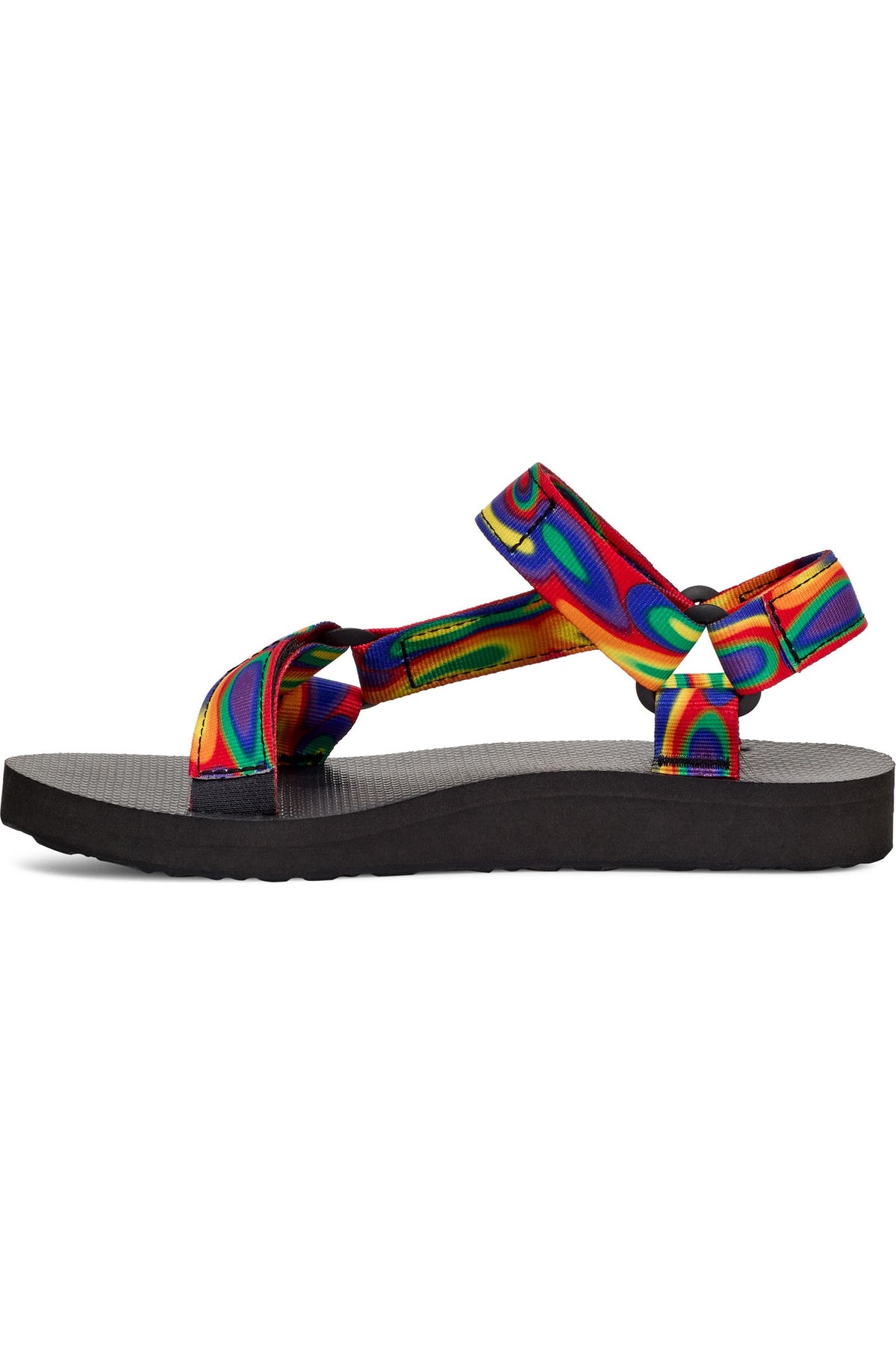 A single T-eeLo sandal shown from the side profile against a solid white background. The sandal features a black footbed and sole, with vibrant, multicolored rainbow-patterned straps.