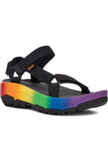 A black Teva sandal with a vibrant rainbow-colored sole, shown from a side profile on a white background.