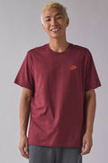 Person wearing a maroon Nike t-shirt against a plain background