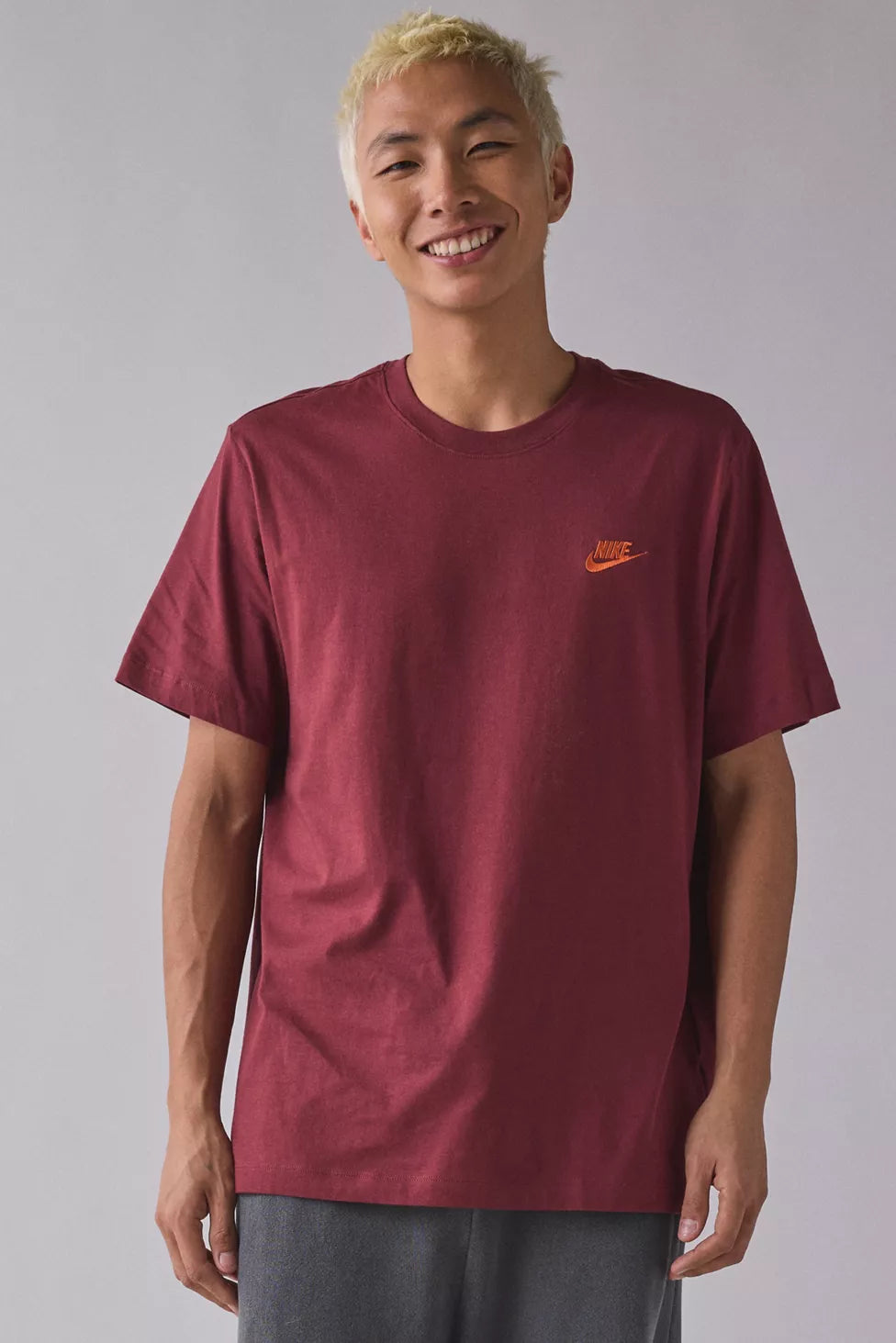 Person wearing a maroon Nike t-shirt against a plain background
