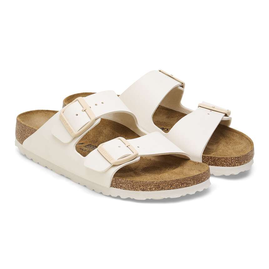 Pair of white sandals with brown soles on a white background