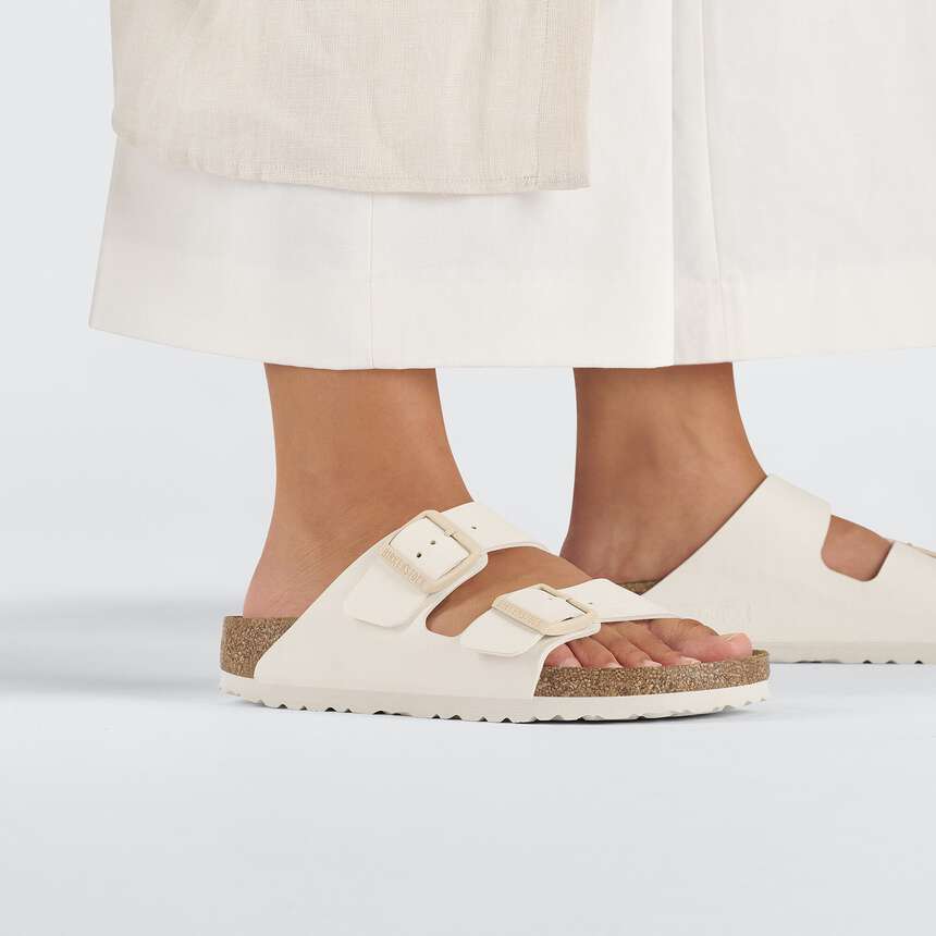 White sandals with cork sole worn by a person on a white background