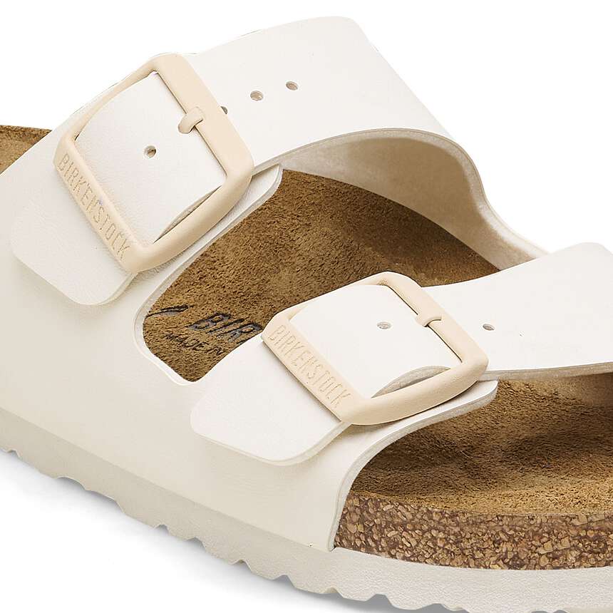 White sandal with beige buckles on a white background